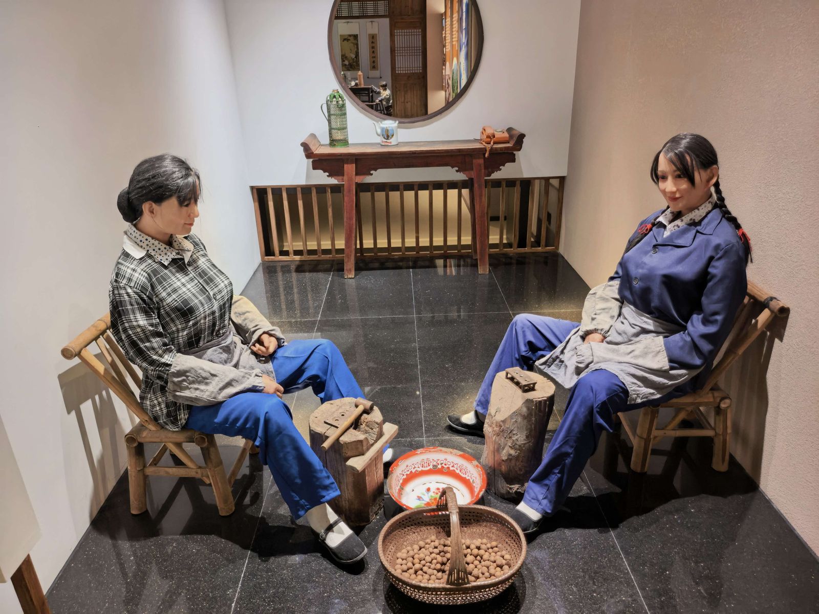 场景复原：两位农家妇女对坐木凳，脚边是敲核桃的木砧与装满原料的竹匾。