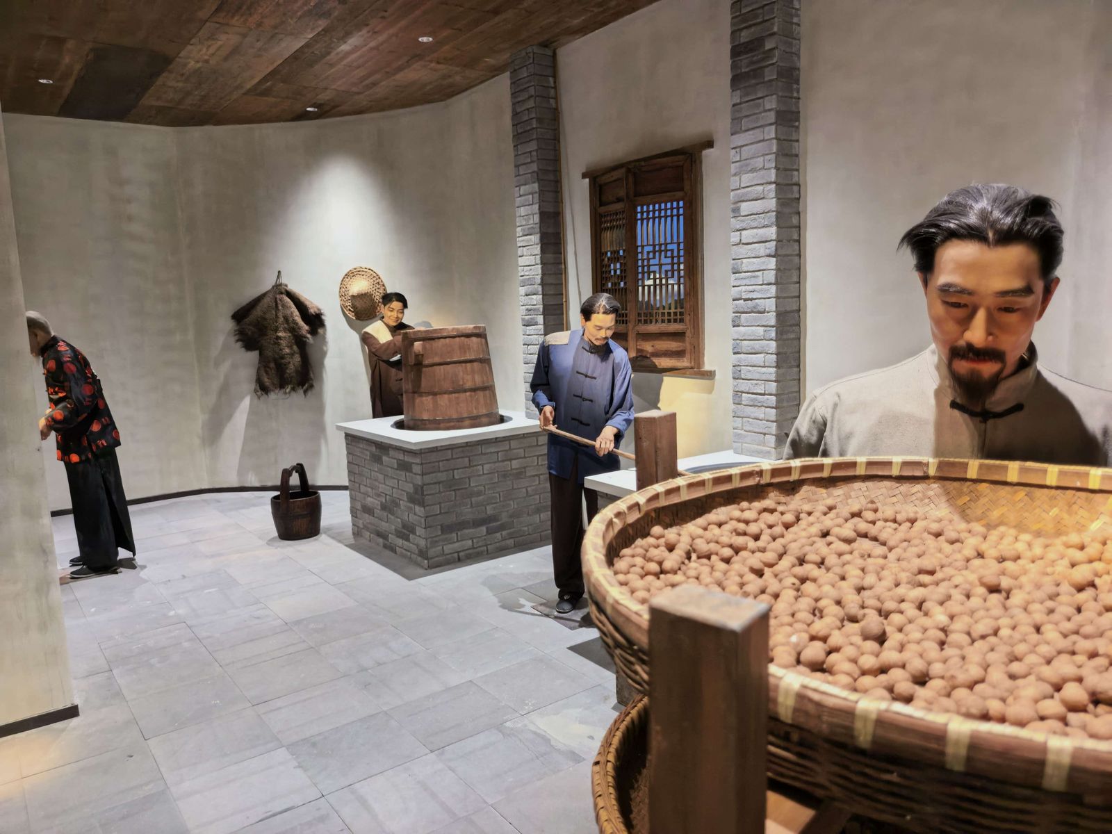 作坊场景复原：土灶上架着木桶，竹匾里堆满山核桃，人物的动作定格在半空。