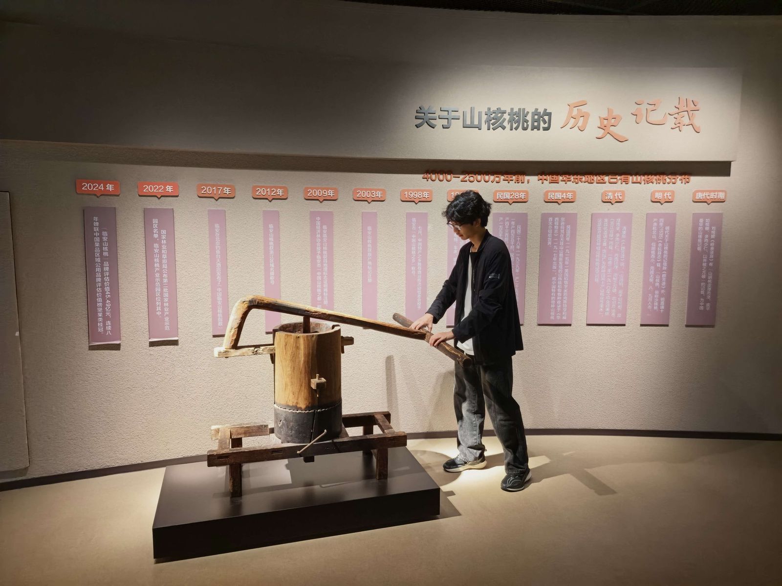 队员上去推了一把木榨的横杠，试试旧时榨油的力道。